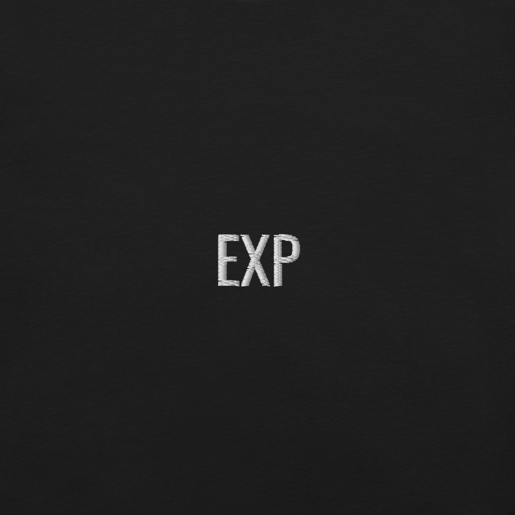 Close-up of embroidered EXP typography on black minimalist t-shirt